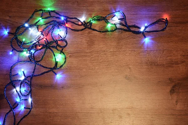 New-year electric garland on a wooden background. Bright bulbs o