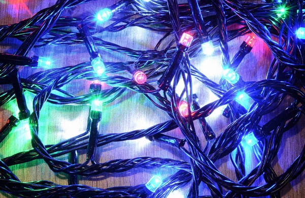 New-year electric garland on a wooden background. Bright bulbs o