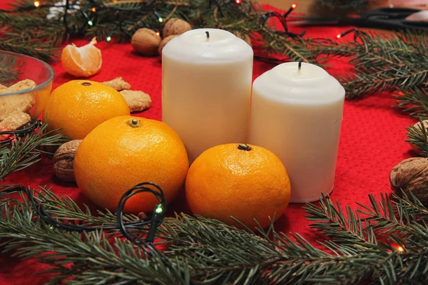 Christmas tree toys on a red napkin. Mandarins and candles on th — Stock Photo, Image