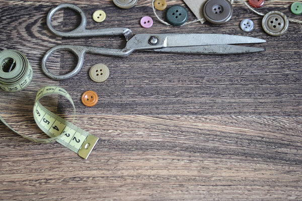 Scissors and buttons on a wooden background