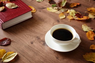 Ahşap masa bir fincan kahve ve bir kitap nesnelerde