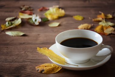 Ahşap masa bir fincan kahve ve bir kitap nesnelerde