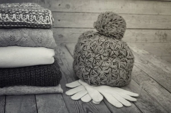 Knitted sweaters and leaves on a wooden background