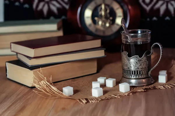 Oude boeken en thee in de avond. Een glas drinken op tafel. De — Stockfoto