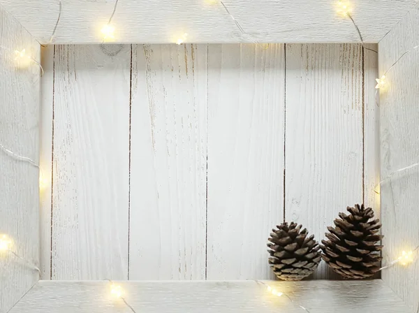 Vánoční světlé girlandy na dřevěné světlé pozadí — Stock fotografie