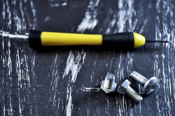 Nueces para reparaciones tumbadas en una mesa de madera. Tuercas y tornillos de hierro f —  Fotos de Stock