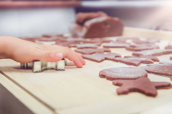 Baking gingerbreads. The family is preparing gingerbreads. The boy\'s handle is holding a mold. Preparing for Christmas, time for the family, cooking and baking together. On the table are arranged gingerbread and molds.