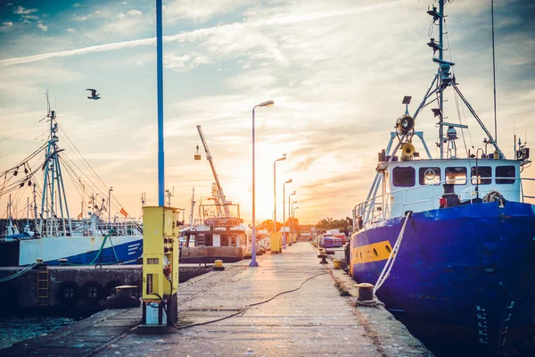 Sail Boats and motor boats moored in part of the harbor and dock with view on amazing and nice sunset. Near sea and parts of fishing boats. Cruise and sea expeditions.