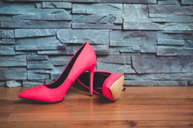 Yüksek topuklu ayakkabılar. Kırmızı topuklu duvar altında bir duruyor yalan. Bir zemin panelleri ve bir arka plan taşlarından oluşur. Moda kavramı.