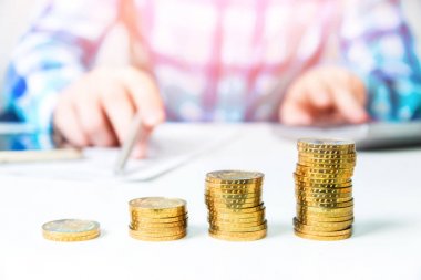 Zenginleştirme ve finansal büyüme kavramı. Altın sikke. El tasarruf para yığmak için ekleyin. Gelir vergisi zammı. Yazılı gol bir kağıt üzerinde işaret eden kişi işyerinde iş planı yazıyor. Hesap makinesi.