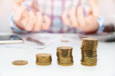 Zenginleştirme ve finansal büyüme kavramı. Altın sikke. Mutsuz adam gest, para tasarrufu. Gelir vergisi zammı. Yazılı gol bir kağıt üzerinde işaret eden kişi işyerinde iş planı yazıyor. Hesap makinesi.