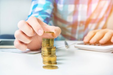Zenginleştirme ve finansal büyüme kavramı. Altın sikke. El tasarruf para yığmak için ekleyin. Gelir vergisi zammı. Yazılı gol bir kağıt üzerinde işaret eden kişi işyerinde iş planı yazıyor. Hesap makinesi.