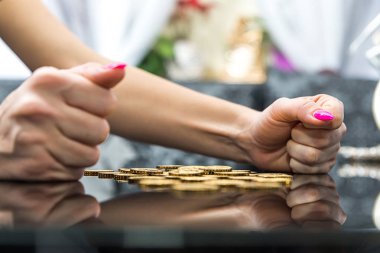 Hand holding golden coins concept. Taxpayer business concept. There are gold coins on the table, a nervous, furious woman has put fists on the table. Earning money, stealing. clipart