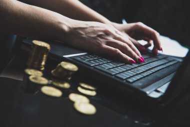 Masada altın sikke, bir sürü bir kadın bir dizüstü bilgisayarda çalışıyor arka planda yer almaktadır. Ev ofis. Kadın çok çalışıyor para kazanmak, iş bilgisayarı, iş kadını, bağımsızlık kavramı.