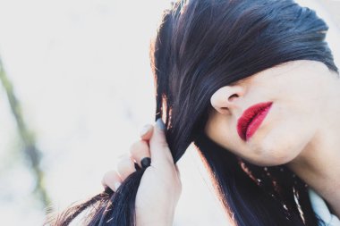 Kadın saçları ile gözleri kapsar. Park açık havada kahverengi saçlı güzel bir kız portresi. Vintage.