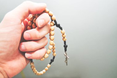 Rosary in hand. A man holds a rosary in his hands, concept of prayer and praying. Christian - Catholic.