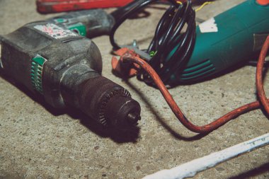 A set of power tools and tools on concrete ground. The concept of industrial work, renovation, physical work. On the ground lies a screwdriver, grinder, wrench.