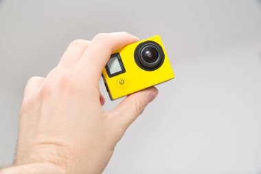 Yellow camera in hand. The man holds the sport camera in his hand. The concept of making sports movies, slow motion.