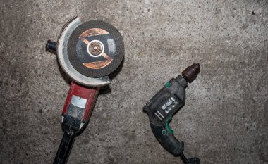 A set of power tools and tools on concrete ground. The concept of industrial work, renovation, physical work. On the ground lies a screwdriver, grinder, wrench.
