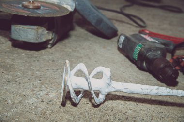A set of power tools and tools on concrete ground. The concept of industrial work, renovation, physical work. On the ground lies a screwdriver, grinder, wrench.