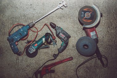 A set of power tools and tools on concrete ground. The concept of industrial work, renovation, physical work. On the ground lies a screwdriver, grinder, wrench.