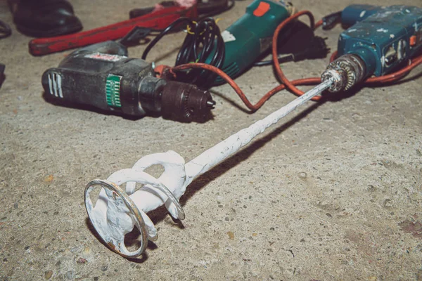 A set of power tools and tools on concrete ground. The concept of industrial work, renovation, physical work. On the ground lies a screwdriver, grinder, wrench.