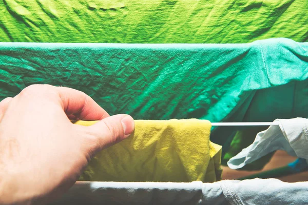 Stacking clothes on the dryer. Clothes drying concept. A man hangs laundry on the dryer, attention to order and cleanliness in the apartment.