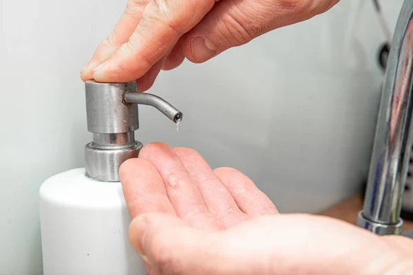 Washing hands with soap. Man takes liquid soap or dishwashing liquid. The concept of care for cleanliness in the kitchen.