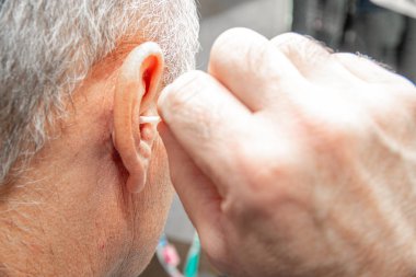 Cleaning the ears with an ear stick. The concept of caring for ear hygiene. Blocked ear, hearing problems. Improper ear cleaning.