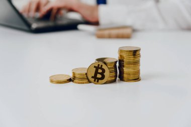 Altın sikke masanın üzerinde. Beyaz masaya vardır bitcoin altın sikke, bir adam inşaat arka planda. Cryptocurrencies üzerinde kazanç finansal büyüme kavramı bitcoin artırır.