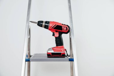 Tornavida merdivenin üzerinde. Dairede tadilat, tasfiye ve planlanan değişiklikler. Bir kırmızı kablosuz ışık arkaplanındadır.