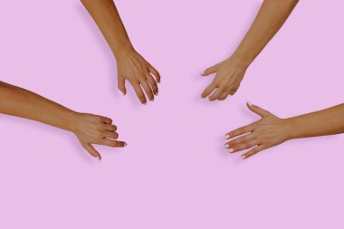 Top view of female hands with nails on a pink, pastel background. Female hands reach for something in the middle of the table. The concept of desire, the desire to receive something.