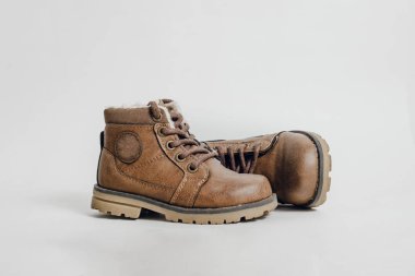 A pair of leather, children's shoes on a light, white background. The concept of upcoming cold, selling shoes. A warm, comfortable shoe for children with fur.