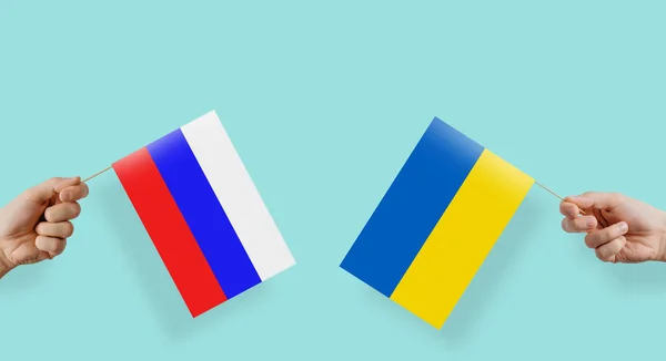 The flags of Russia and Ukraine are kept in their hands. The hand raises the flag of Russia and Ukraine. The concept of relations between States, economic community, politics. Conflict in Ukraine.