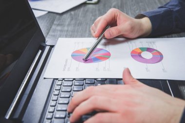 İş adamı raporlardaki bilgileri analiz eder. Adam mali belgelerdeki verileri kontrol ediyor. Finansal rapor, ekonomik konsept. Giderlerin, maliyetlerin, karların, kayıpların analizi.