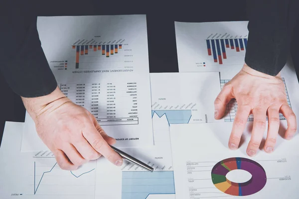 Analyst is working on reports and graphs. The man analyzes the graphs of reports, checks costs and revenues. Financial growth, market research. The development of companies and corporations.