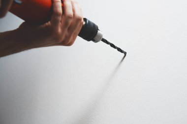 Duvar delme. Adam bir tornavida ya da matkap elinde tutuyor. Bir matkapla bir matkap kullanarak duvarda bir delik matkap. Ev işleri, Ev Tadilat, ev kavramı.