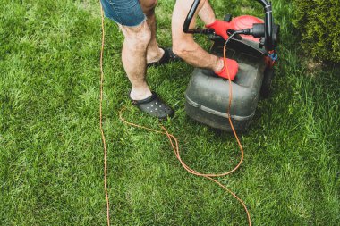 Çim biçme üzerinde yukarıdan. Bahçıvan çim ile kırmızı bir elektrik biçme mows. Bahçe, bahar temizliği işe. Bahçe ve çim bakımı.