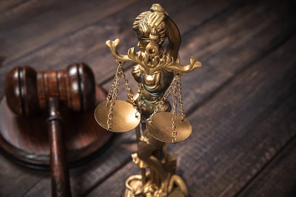 Judges gavel and Themis on a wooden table top, dark background. The concept of justice and dealing with court cases. Citizens\' problems in courts, honesty. Symbols of judge and courts. Sense of justice.