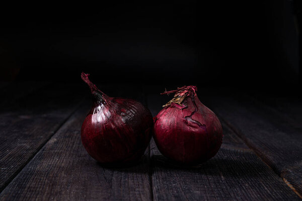 Red onion on a wooden background. The concept of food and cooking. Eating vegetables and healthy nutrition. Eating red onions, adding to dishes.