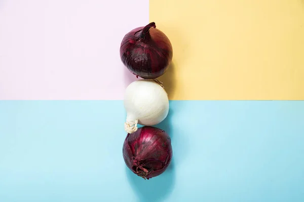 Red onion and white onion on a pastel background. The concept of food and cooking. Eating vegetables and healthy nutrition. Eating red onions, adding to dishes.