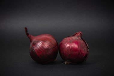 Siyah arka planda kırmızı soğan. Yemek ve yemek yapma kavramı. Sebze yemek ve sağlıklı beslenme. Kırmızı soğan yiyorum, tabakları ekliyorum..