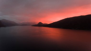 Güzel kırmızı gün batımı Norveçli kıyı şeridi arkasında.