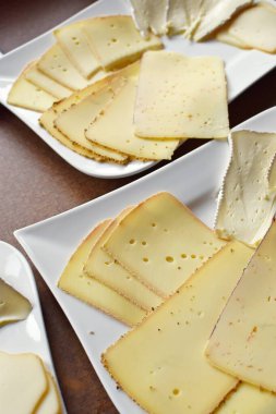 Farklı peynir türleriyle dolu beyaz bir tabak. Almanya 'da akşam yemeği için beyaz bir tabakta dilimlenmiş peynir.