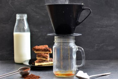 Fındık köşeleri, şeker ve süt dolu koyu bir arka plana karşı filtre torbasından taze buğulanmış kahve.