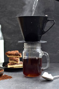 Fındık köşeleri, şeker ve süt dolu koyu bir arka plana karşı filtre torbasından taze buğulanmış kahve.