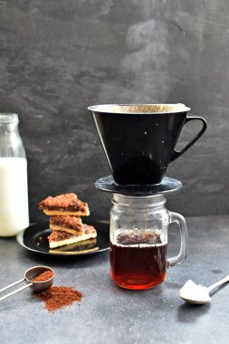 Fındık köşeleri, şeker ve süt dolu koyu bir arka plana karşı filtre torbasından taze buğulanmış kahve.