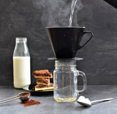 Fındık köşeleri, şeker ve süt dolu koyu bir arka plana karşı filtre torbasından taze buğulanmış kahve.