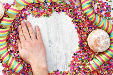 Almanya 'dan gelen karnaval çörekleri, üzerinde konfeti ve flamalar olan hafif ahşap bir yüzeyde krema şekeri ile bir karnaval partisi ya da partiler için arka plan.