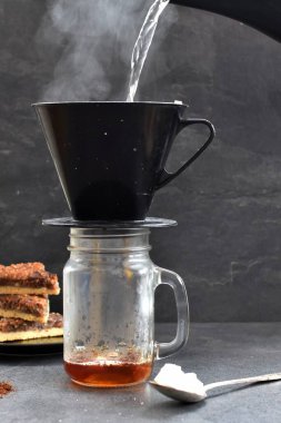 Fındık köşeleri, şeker ve süt dolu koyu bir arka plana karşı filtre torbasından taze buğulanmış kahve.